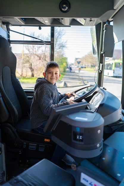 A boy drive a bus the boy turns the steering wheel in the\
abandoned bus the boy is playing on the bus
