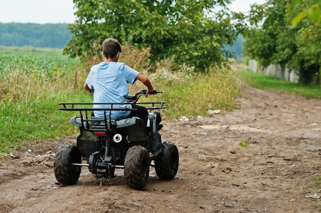 Мальчик водит четырехколесный квадроцикл ATV