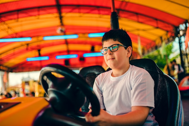 Ragazzo che conduce l'automobile di paraurti in parco di divertimenti