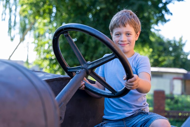 A boy driving an old vintage tractor in the background of a brick wall
