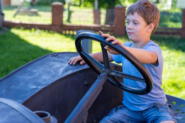 A boy driving an old vintage tractor in the background of a brick wall