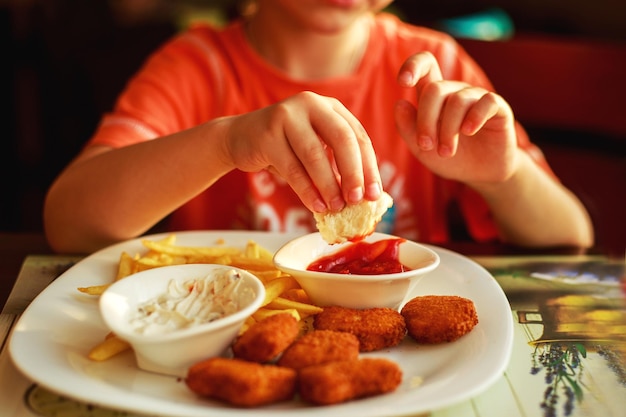 カフェでファーストフードを食べる男の子ナゲットとフライドポテトを食べる子供