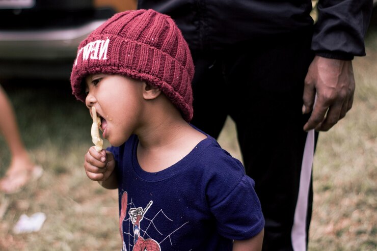 Photo 外に立ってアイスクリームを食べている少年