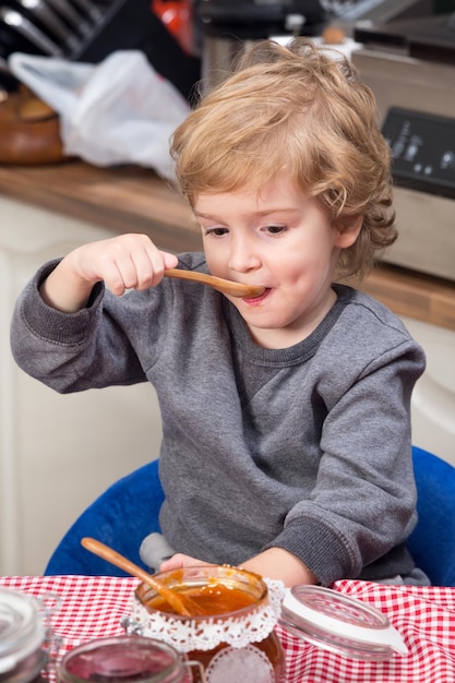 Boy eating jam with bread on table