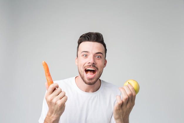 Boy eats a carrot and apple.