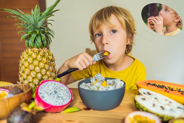 Boy eats fruit but dreams about hamburger Harmful and healthy food for children Child eating healthy snack Vegetarian nutrition for kids Vitamins for children Junk food concept