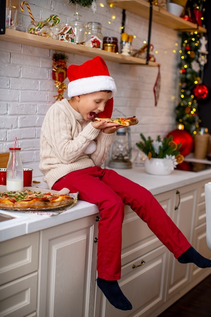 Photo the boy eats a piece of hot pizza