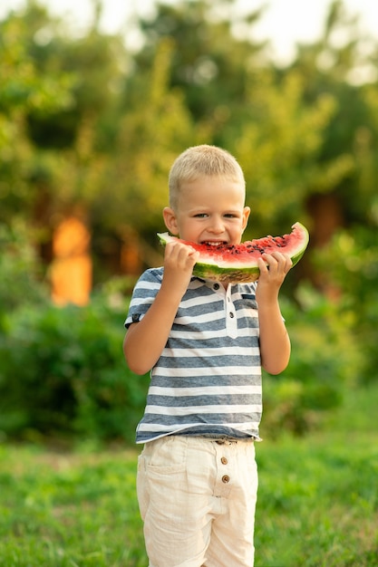 소년은 야외에서 수박을 먹는다. 시골에서 여름 휴가입니다.