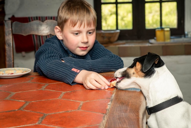 Foto un bambino di otto anni mangia a tavola con un cane