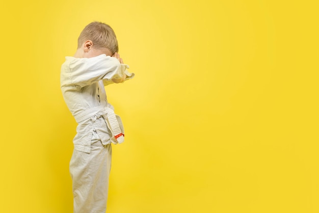 Ragazzo impegnato nel karate su un muro giallo. lezioni di judo, stile di vita sportivo aikido.