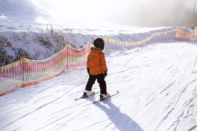 装備の少年が雪の斜面でスキーをしている