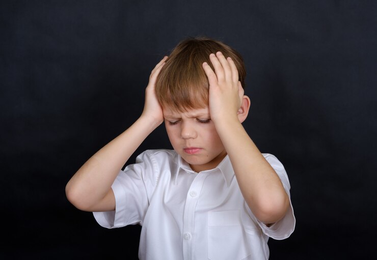 Boy European appearance holding his head in pain. headache concept. isolate on a black