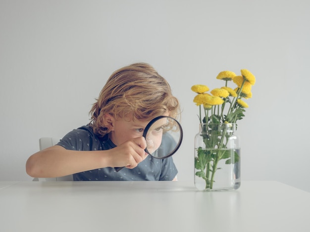 Boy examining flowers with magnifier