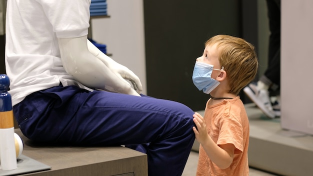 Boy examining mannequin in shop during quarantine