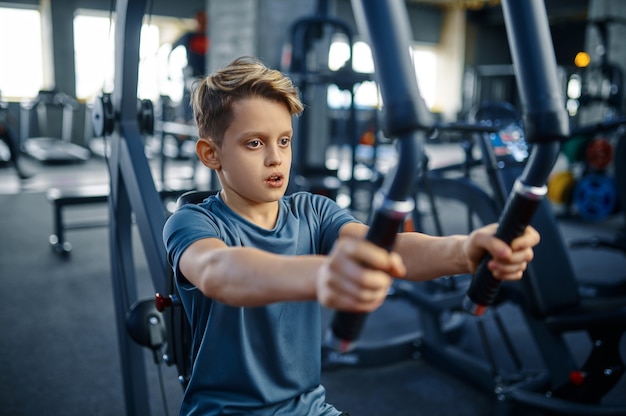 Boy on exercise machine, fit training in gym. Youngster in sport club, healthcare and healthy lifestyle, schoolboy on workout, sportive youth