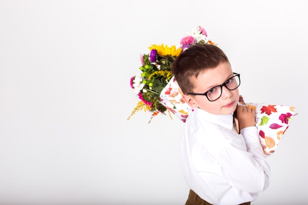 白い背景の上の花の花束を目の眼鏡の少年