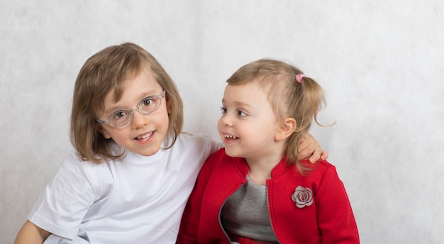 Boy of five years and girl of 2 years are staying together. Gray background.