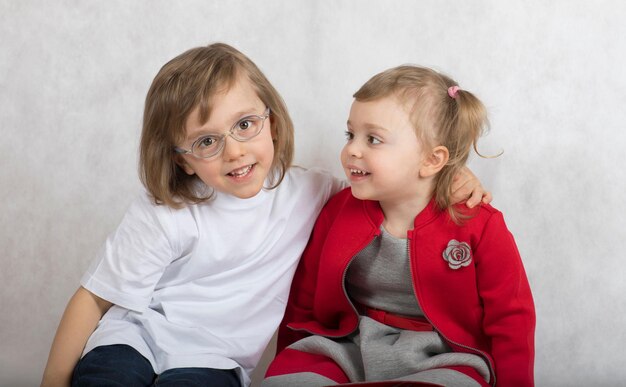 Foto un ragazzo di cinque anni e una ragazza di 2 anni stanno insieme. sfondo grigio.