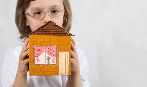 Boy of five years is keeping handmade carton paper house. Closeup