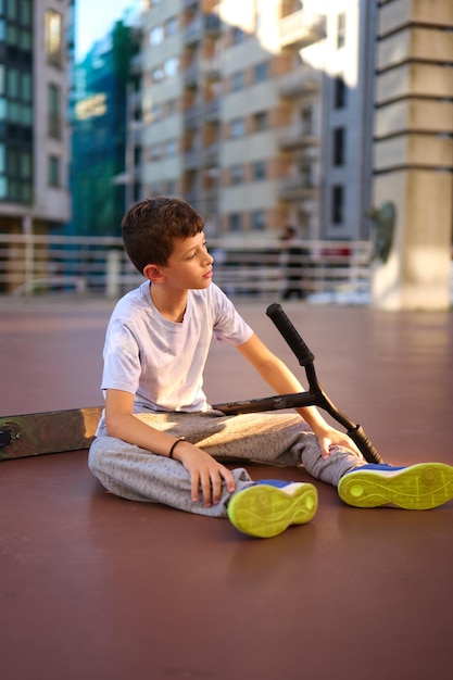 Boy on the floor with his scooter stunt on the street