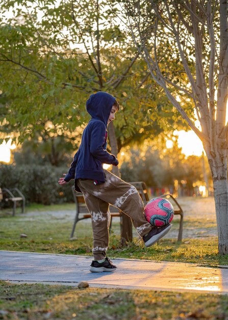 Boy football soccer player doing ball tricks on nature at sunset Lifestyle outdoors concept