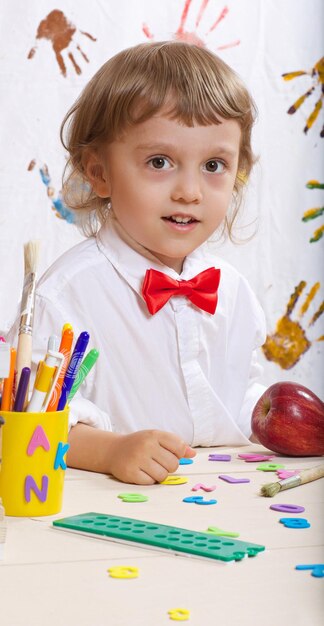 Boy of four years old dressed in white shirt with red bow. Back to school background.