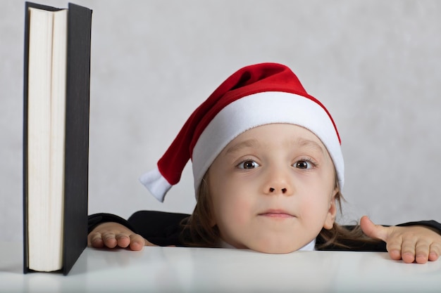 Boy of four years in Santa's hat close to the book. Closeup