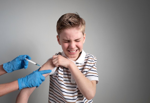 The boy gets an injection in his arm