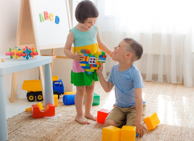 男の子と女の子は、ハートのプラスチックブロックを保持しています。兄弟姉妹は部屋で一緒に遊んで楽しんでいます。