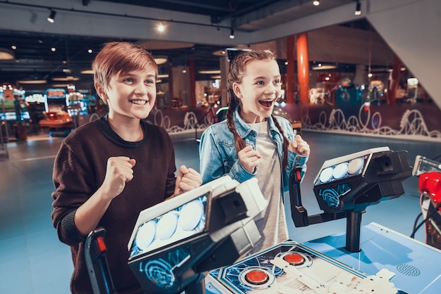 Boy and girl are piloting blue spacecrafts playing in arcade