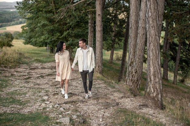 A boy and a girl are walking hand in hand through the woods