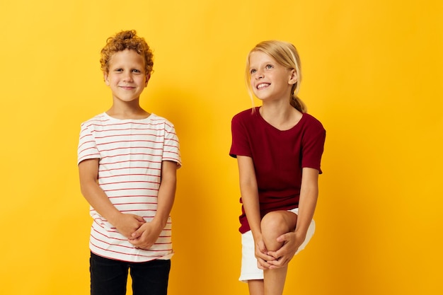 Мальчик и девочка повседневная одежда игры весело вместе желтый фон