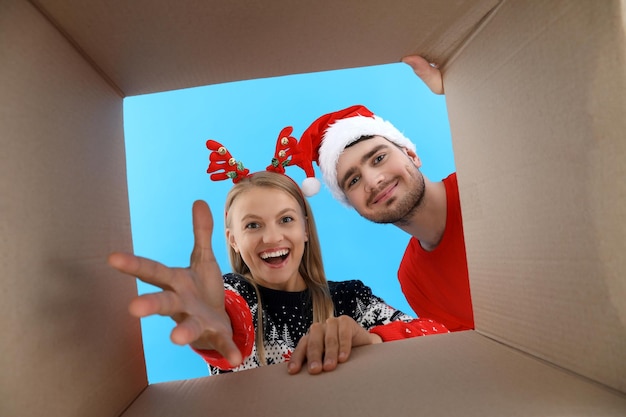 A boy and a girl in Christmas hats look into the box