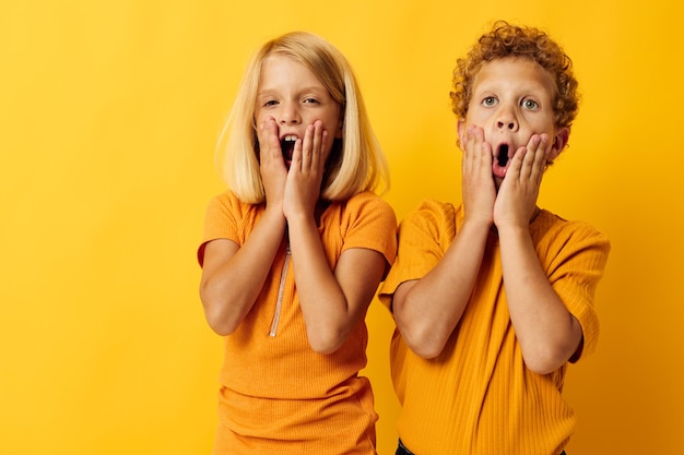 男の子と女の子がファッションの子供時代のエンターテイメントを抱きしめる孤立した背景