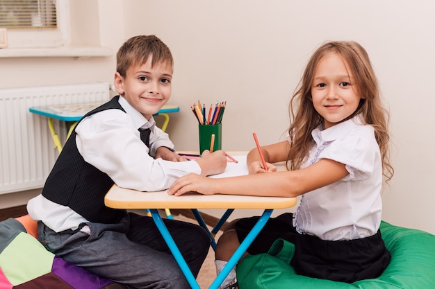 Мальчик и девочка рисуют карандашами за столом