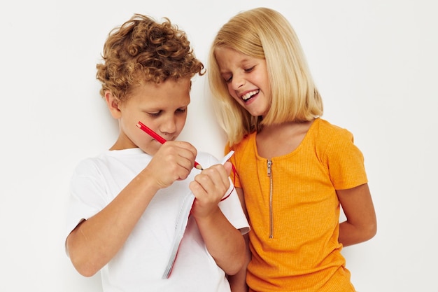 Boy and girl fun in colorful tshirts with a notepad isolated background unaltered