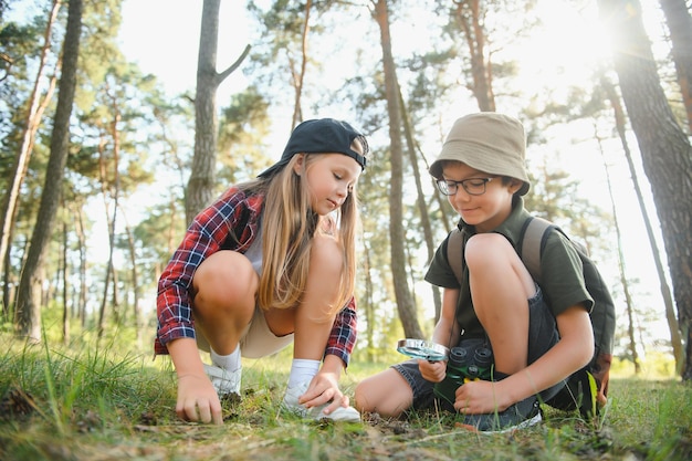 Boy and girl go hiking with backpacks on forest road bright sunny day