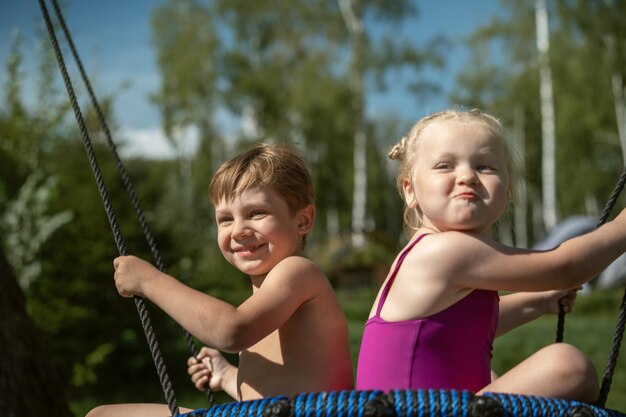소년과 소녀 놀이터에서 거미줄 나무 스윙에 재미 자연 여름 휴가