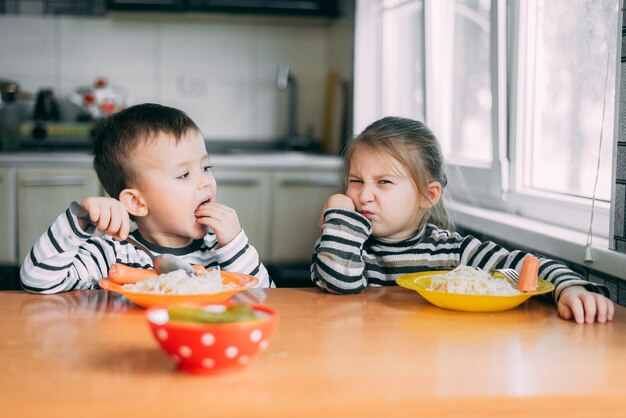 パスタを食べる台所の男の子と女の子