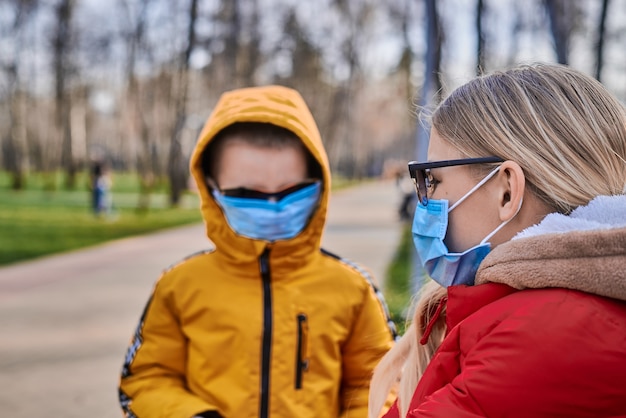 Ragazzo e ragazza in maschere mediche nel parco primaverile