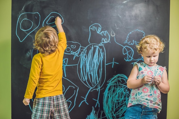 Boy and girl paint with chalk on a blackboard