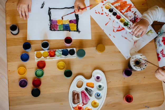 A boy and a girl play together and paint. Recreation and entertainment. Stay at home.