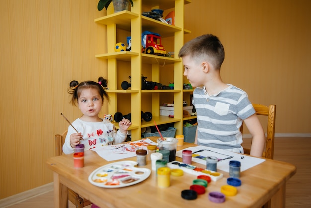 A boy and a girl play together and paint. Recreation and entertainment. Stay at home.