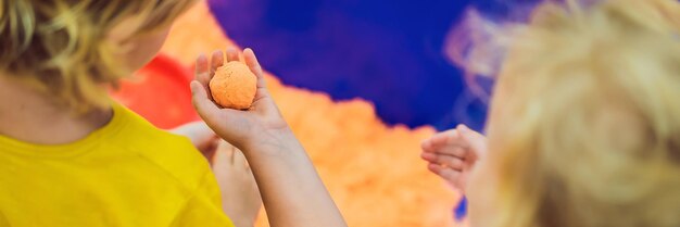 Boy and girl play with kinetic sand banner long format