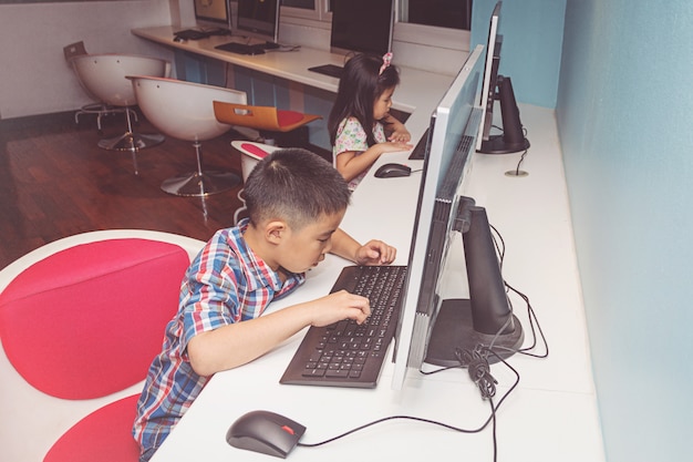 Photo boy and girl playing with a computer