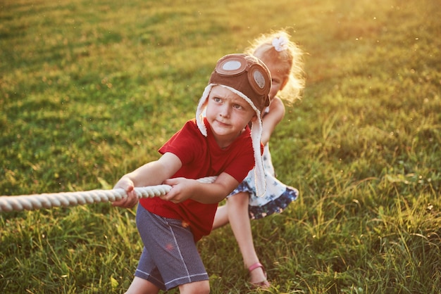 Boy and girl pulling a rope and playing tug of war at the park