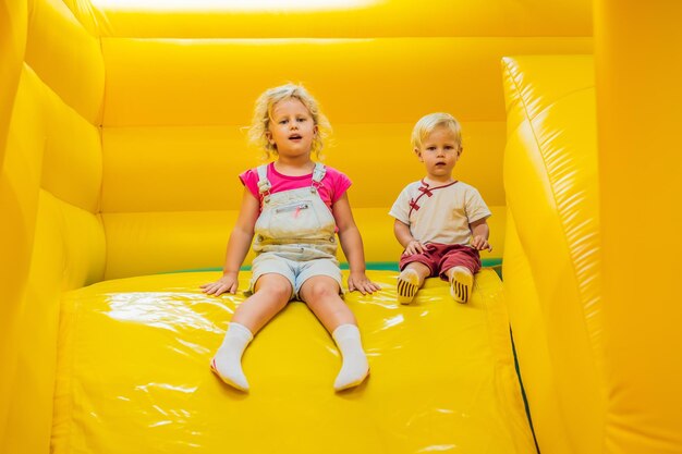 A boy and a girl ride from an inflatable slide