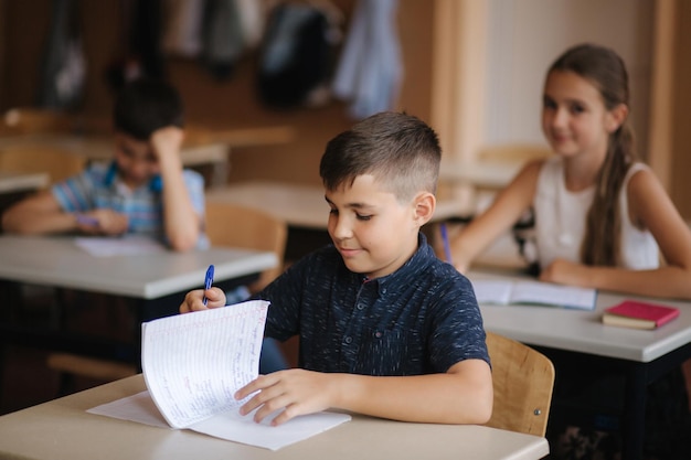 Boy and girl sitting at desk and writing a text