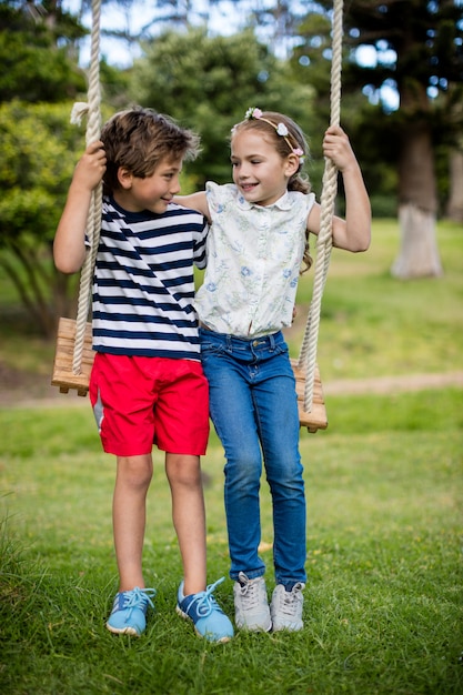 Boy and girl sitting on a swing in park