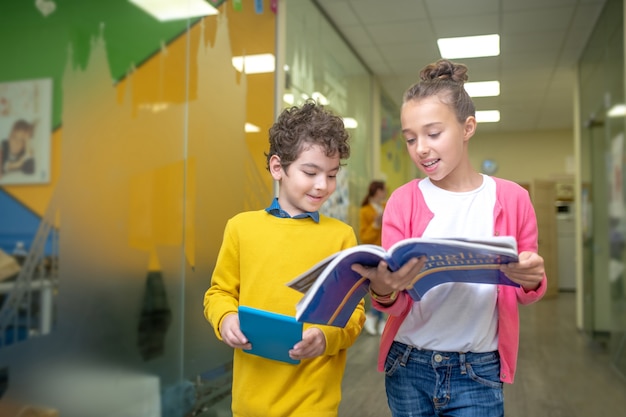 教科書を手に廊下に立っている男の子と女の子